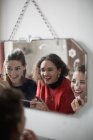 Young women friends getting ready, applying makeup in bathroom mirror — Stock Photo