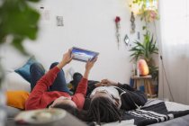 Молода пара розслабляється, використовуючи цифровий планшет на ліжку — стокове фото