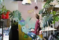 Чоловічий художник малює на великому полотні в квартирі — стокове фото
