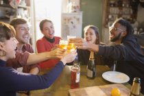 Young adult friends toasting cocktails at apartment kitchen table — Stock Photo