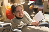 Портрет усміхнений, щаслива молода жінка читає книгу в кріслі — стокове фото