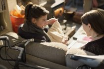 Giovani coinquiline che lavorano a maglia sul divano del soggiorno — Foto stock