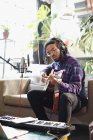Молодой человек записывает музыку, играет на гитаре и поет в микрофон в квартире — стоковое фото
