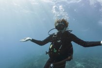 Portrait young woman scuba diving underwater with arms outstretched — Stock Photo