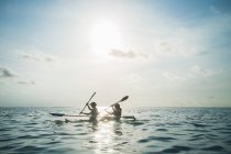 Женщины в чистом нижнем каноэ на солнечном, идиллическом океане, Мальдивах, Индийском океане — стоковое фото