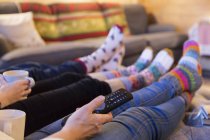 Family in colorful socks relaxing, watching TV in living room — Stock Photo