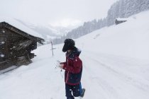 Menino adolescente andando fora da cabana de montanha nevada, Forclaz, Suíça — Fotografia de Stock