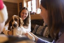 Mother and daughter playing with dog in living room — Stock Photo