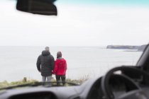 Couple looking at ocean view outside car — Stock Photo