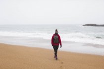 Жінка з рюкзаком ходить на зимовому пляжі — стокове фото