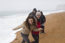 Famiglia felice e spensierata sulla spiaggia invernale innevata — Foto stock