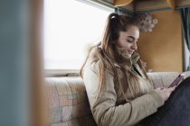Девушка-подросток пишет смс со смартфона в доме на колёсах — стоковое фото
