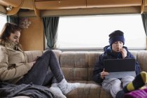 Irmão adolescente e irmã usando tablet digital e telefone inteligente em casa de motor — Fotografia de Stock