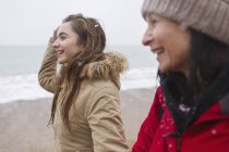 Happy mother and daughter walking on snowy beach — Stock Photo