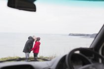 Casal afetuoso beijando fora motor casa no penhasco com vista para o oceano — Fotografia de Stock