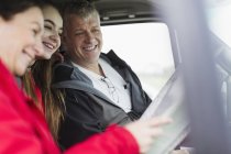 Los padres y la hija mirando el mapa en autocaravana - foto de stock