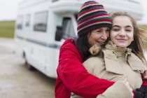 Liebevolle Mutter und Tochter in warmer Kleidung umarmen sich vor dem Wohnmobil — Stockfoto