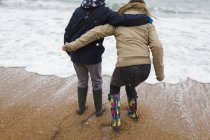 Playful teenage brother and sister playing in winter ocean surf — Stock Photo