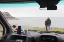 Casal conversando fora motor home no penhasco com vista para o oceano — Fotografia de Stock