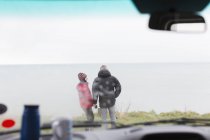 Couple standing outside of motor home on cliff overlooking ocean — Stock Photo