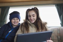 Teenage brother and sister using digital tablet in motor home — Stock Photo