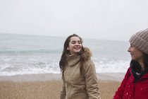Mother and daughter in warm clothing walking on winter ocean beach — Stock Photo