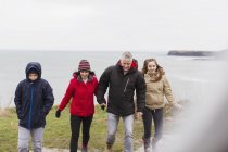 Family in warm clothing on cliff overlooking ocean — Stock Photo
