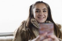 Улыбающаяся портрет, уверенная в себе девочка-подросток, которая пишет смс со смартфона — стоковое фото