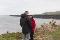 Paar spricht auf Klippe mit Blick auf Ozean — Stockfoto