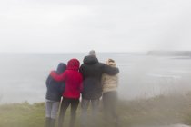 Family in warm clothing enjoying ocean view — Stock Photo