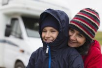 Affectionate mother and son in warm clothing hugging outside motor home — Stock Photo