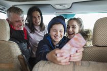 Счастливая семья со смартфоном в автомобильном доме — стоковое фото