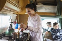 Mujer sonriente cocinando en autocaravana - foto de stock