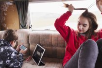 Adolescent frère et sœur détente, en utilisant une tablette numérique et téléphone intelligent dans le camping-car — Photo de stock