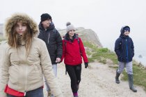 Family in warm clothing walking on snowy winter cliff path — Stock Photo