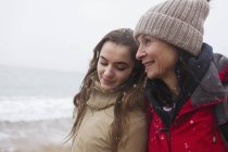 Affectionate mother and daughter on snowy winter beach — Stock Photo