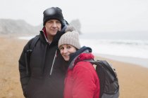 Portrait couple in warm clothing on winter beach — Stock Photo