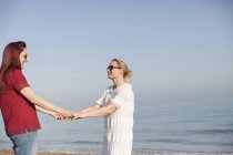 Casal lésbico afetuoso de mãos dadas na praia ensolarada do oceano — Fotografia de Stock