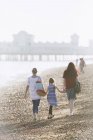 Лесбийская пара и дочь держатся за руки на солнечном пляже — стоковое фото
