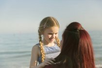 Прихильна мати тримає дочку на пляжі сонячного океану — стокове фото