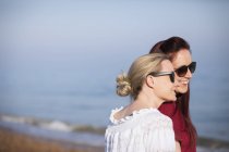 Affectionate lesbian couple on sunny beach — Stock Photo