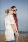 Liebevolles lesbisches Paar hält Händchen am sonnigen Strand — Stockfoto