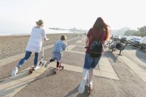 Lesbisches Paar mit Tochter fährt Schubkarren auf sonniger Strandpromenade — Stockfoto