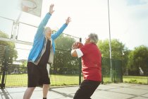 Hommes seniors actifs jouant au basket dans un parc ensoleillé — Photo de stock