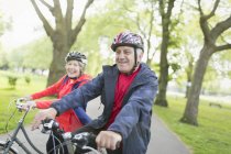 Active senior couple riding bikes in park — Stock Photo
