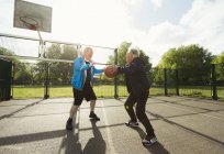 Aktive Senioren spielen Basketball im sonnigen Park — Stockfoto