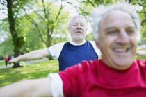 Hombres mayores activos haciendo ejercicio, estirándose en el parque - foto de stock