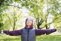 Portrait serene active senior woman stretching in park — Stock Photo