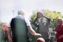 Active senior men playing basketball in sunny park — Stock Photo