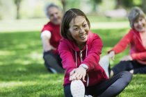 Happy active senior woman stretching leg in park — Stock Photo